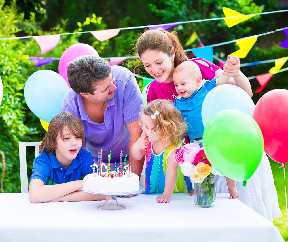 Famille de trois enfants fêtant un anniversaire autour d'un gâteau