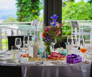Table dressée avec verres à pieds, bouquet de fleurs et cadeaux